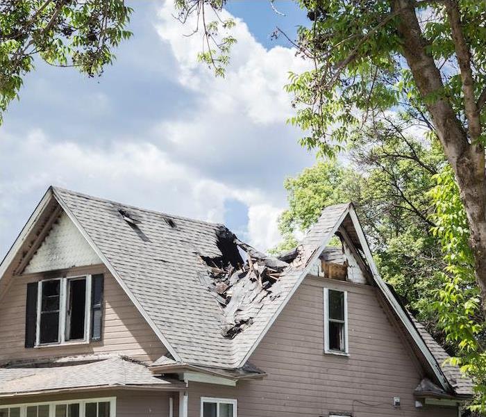 residentail home with roof destroyed and debris falling down